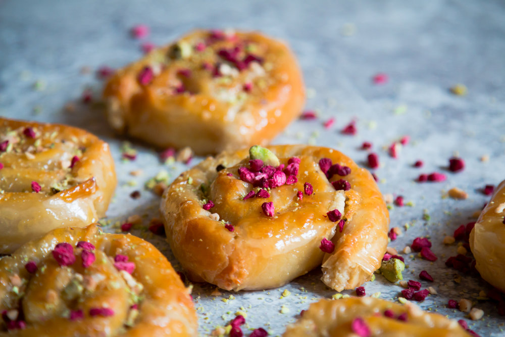 Rolled-up filo pastry glazed with honey and topped with dried raspberry pieces and crushed almonds.