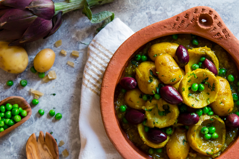 Bowl with baby potatoes, green peas, lemon and artichoke.